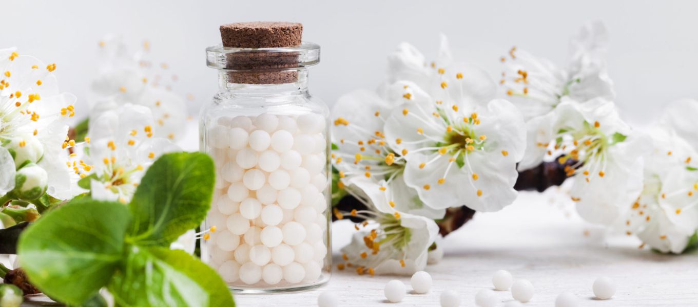 Glazen pot met witte balletjes en appelbloesem